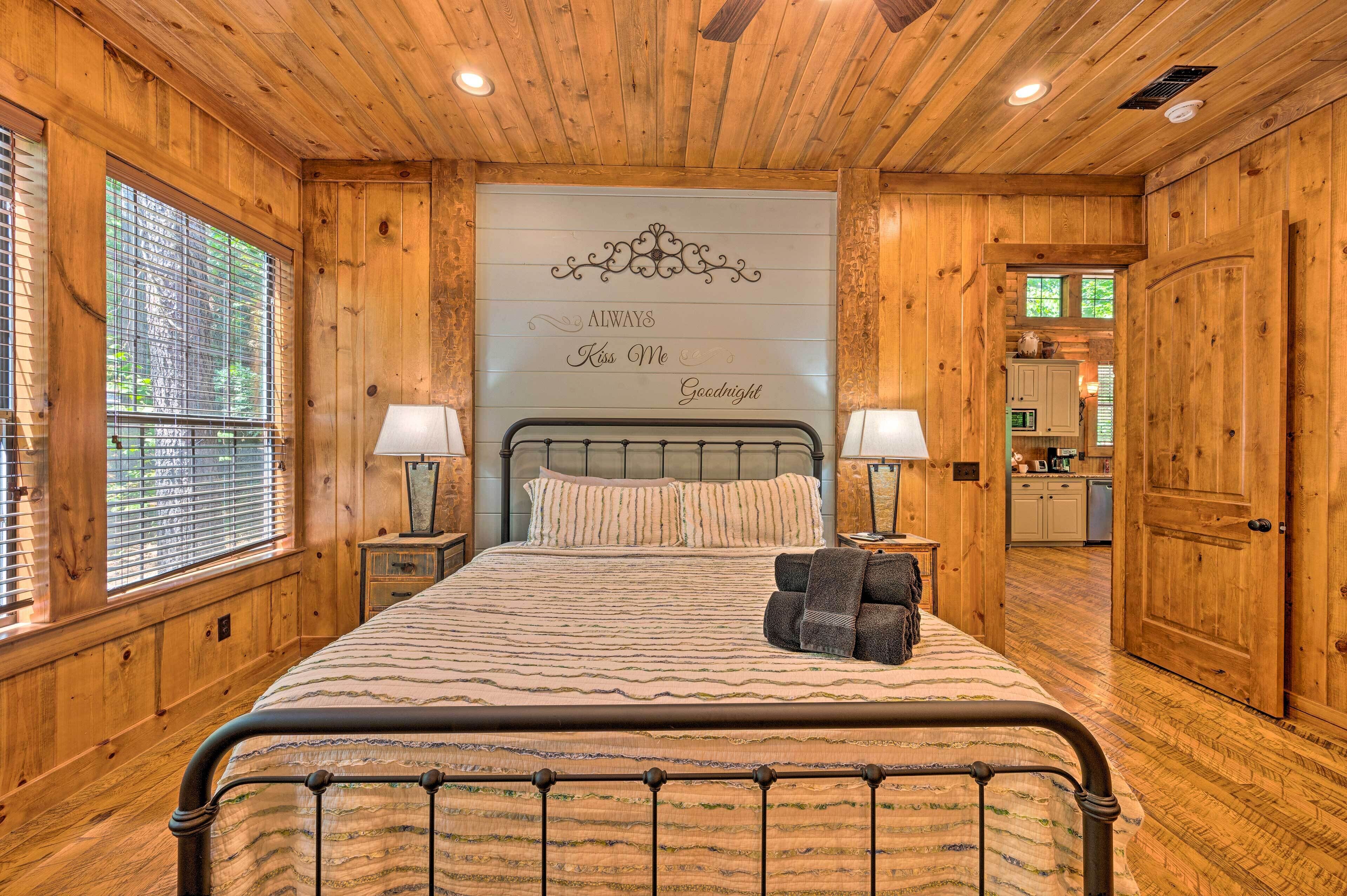 A wooden-paneled bedroom with a bed, two bedside lamps, and a decorative wall sign.