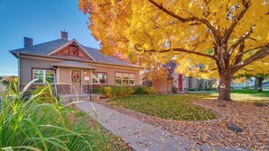 A house with a stone chimney, a front porch, and a well-maintained lawn with autumn leaves. - Charming Getaway, Walk to Windsor Lake & Downtown! (Windsor)