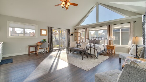 A spacious living room with a high ceiling, large windows, and a ceiling fan. - Charming Getaway, Walk to Windsor Lake & Downtown! (Windsor)