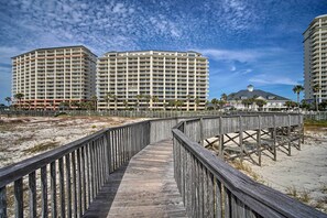 Une promenade en bois mène à des hôtels situés en bord de mer, dotés de plusieurs étages et de balcons.
