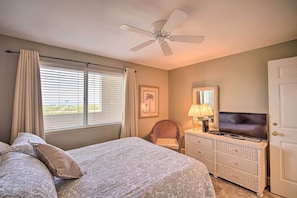 A bedroom with a bed, a ceiling fan, a dresser, a TV, and a window with blinds. - Waterfront Gulf Shores Escape w/ Resort Amenities! (Gulf Shores)