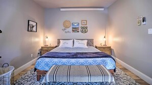 A bedroom with a bed, bedside tables, a ceiling fan, wall decorations, and a rug.
