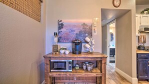 A kitchen with a wooden island featuring a microwave, coffee maker, and storage baskets.