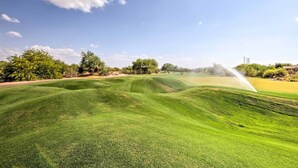 Ein Golfplatz mit gepflegtem Rasen, Bäumen und blauem Himmel.