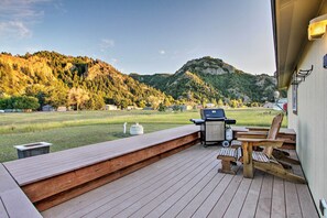 A deck with a grill and chairs overlooking a grassy area and mountains. - Craig Area Fly Fishing Hot Spot: Walk to River! (Cascade)