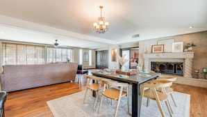 A spacious living room with a fireplace, a dining area with wooden chairs, and a large window with blinds. - 2 Mi to Old Town: 'the Grand Palms Estate' w/ Pool (Scottsdale)