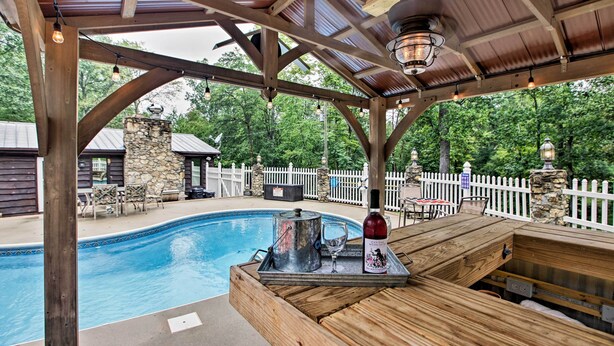 Una terraza de madera con piscina, chimenea de piedra y zona de estar al aire libre.