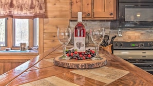 Una encimera de madera con una botella de vino Chateau Morisette, dos copas y una guirnalda decorativa de bayas.