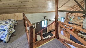Una cabaña de madera con habitación en la buhardilla, comedor y cocina.