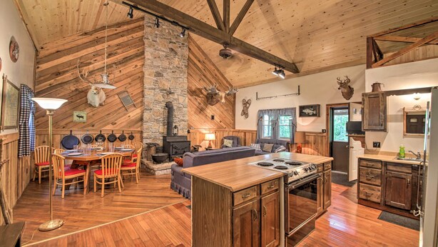 Una cocina amplia con una isla grande, vigas de madera, detalles de piedra y decoración rústica.