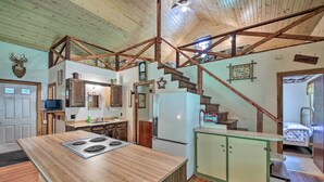 Una cocina rústica con una isla de madera, un refrigerador y una escalera que lleva a una zona de altillo.
