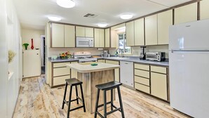 A compact kitchen with a central island, white appliances, and a wooden floor. - Sedona Stardust Hideaway' w/ Patio & Mtn Views! (Sedona)