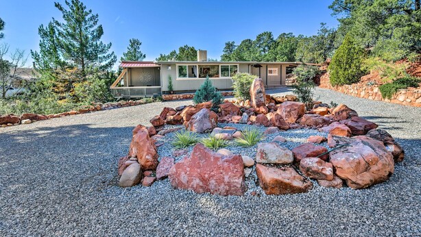 A modern house with a stone foundation, surrounded by a rock garden and pine trees. - Sedona Stardust Hideaway' w/ Patio & Mtn Views! (Sedona)
