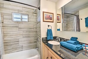Un baño con ducha, lavamanos y espejo.