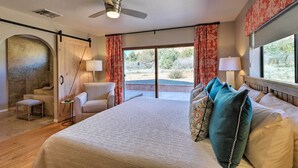 A bedroom with a large bed, a ceiling fan, a chair, a small table, and a view of the outdoors. - Secluded Sedona Escape w/ Patio & Red Rock Views! (Sedona)