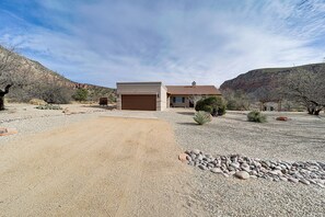 A modern house with a garage, surrounded by a gravel driveway and sparse vegetation.