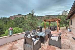 An outdoor patio with wicker furniture, a glass-top table, and a pergola.