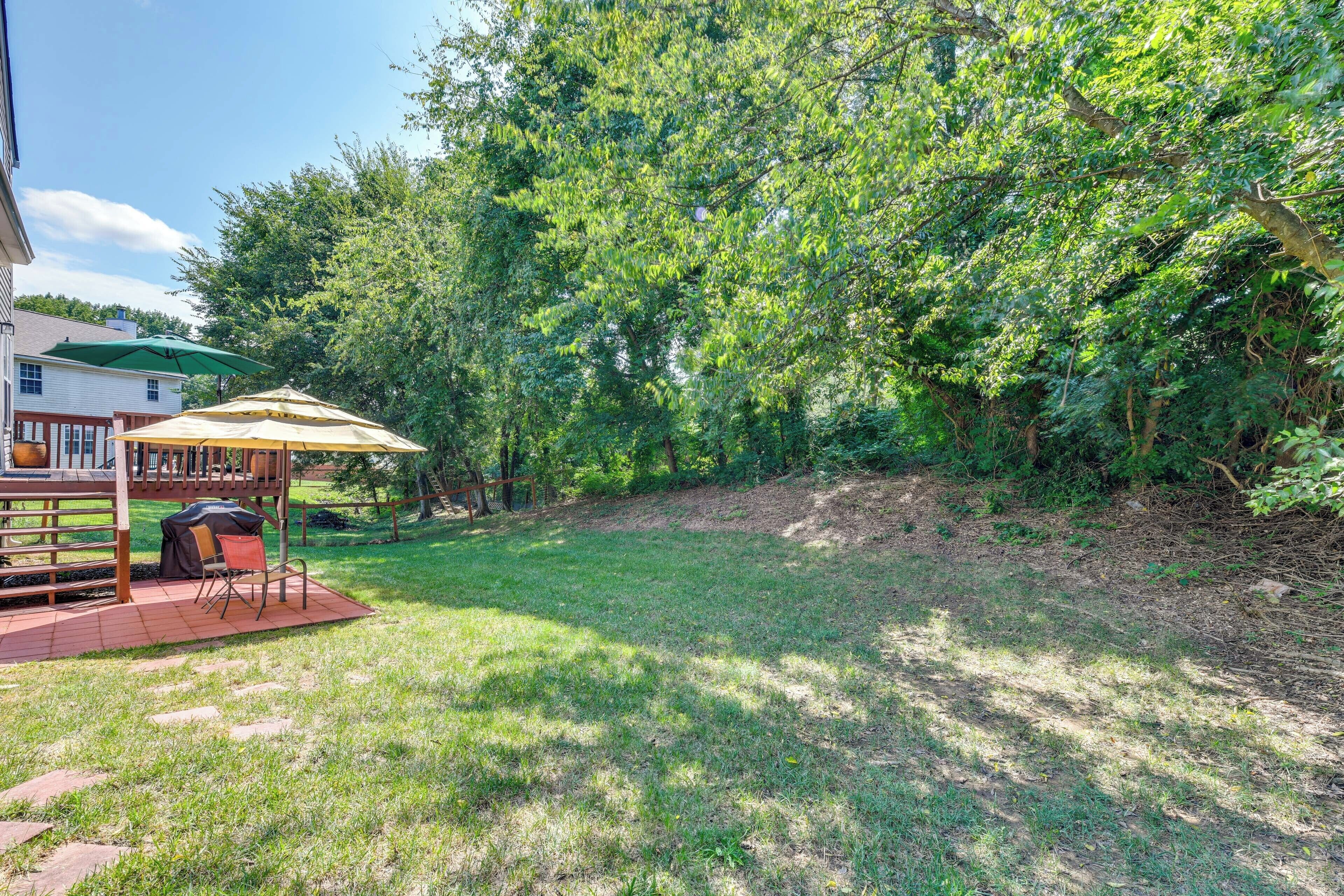 Ein Garten mit einer Holzterrasse, Gartenmöbeln und einem überdachten Sitzbereich.