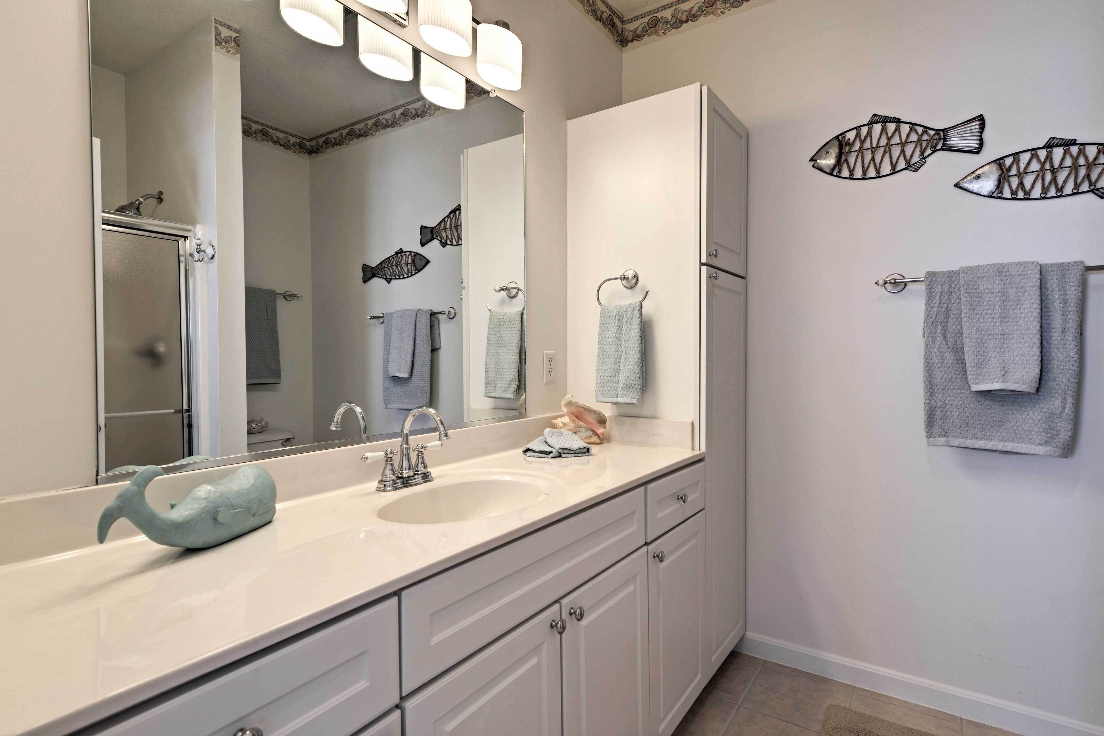 A bathroom with a large mirror, two sinks, and decorative fish wall art.