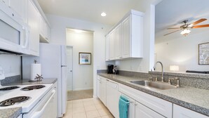 A modern kitchen with white cabinets, a granite countertop, a stainless steel sink, and a ceiling fan. - 4 Mi to Beaches: Luxe Coastal Resort Condo (Lewes)