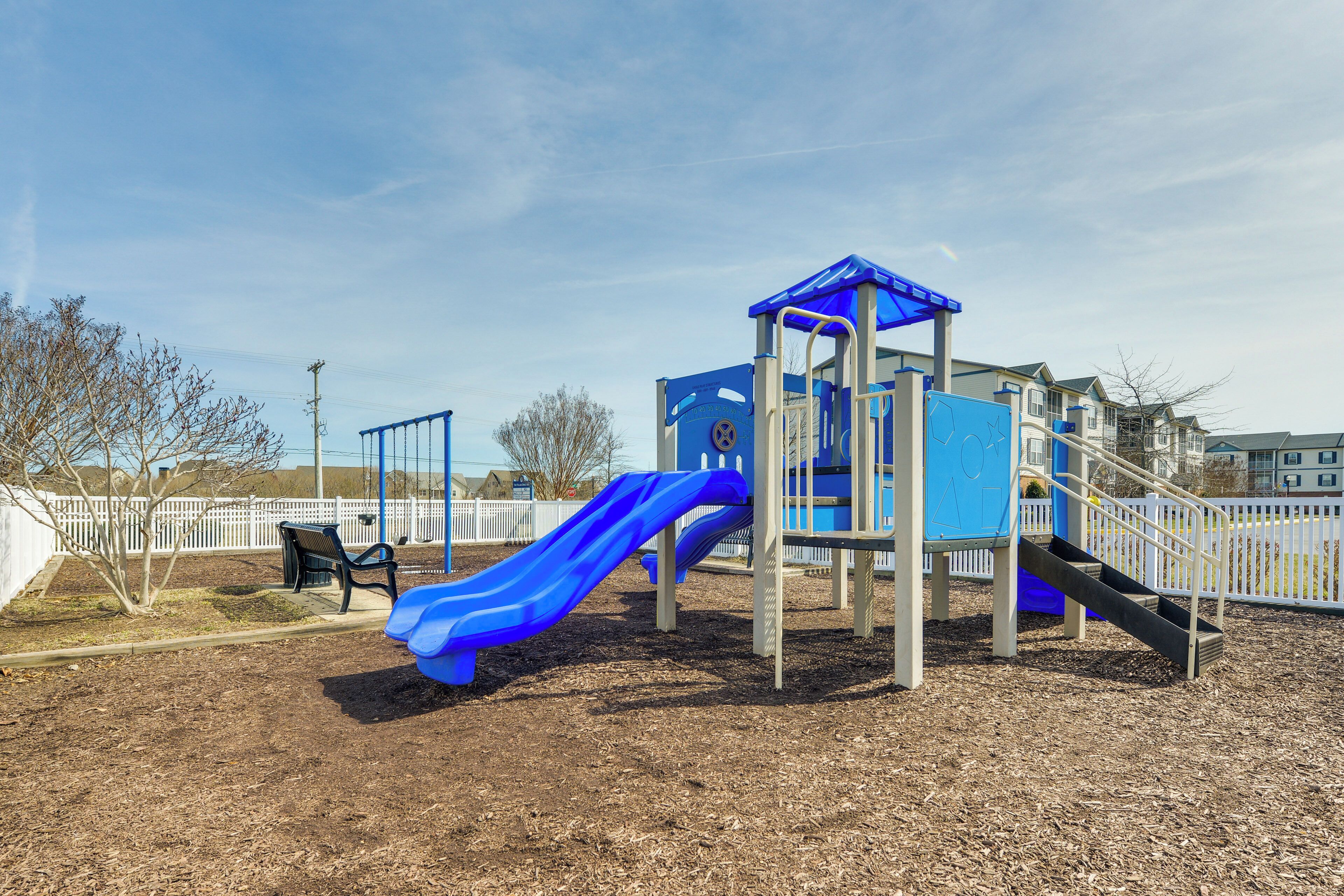 Une aire de jeux avec un toboggan bleu et une petite structure d’escalade.