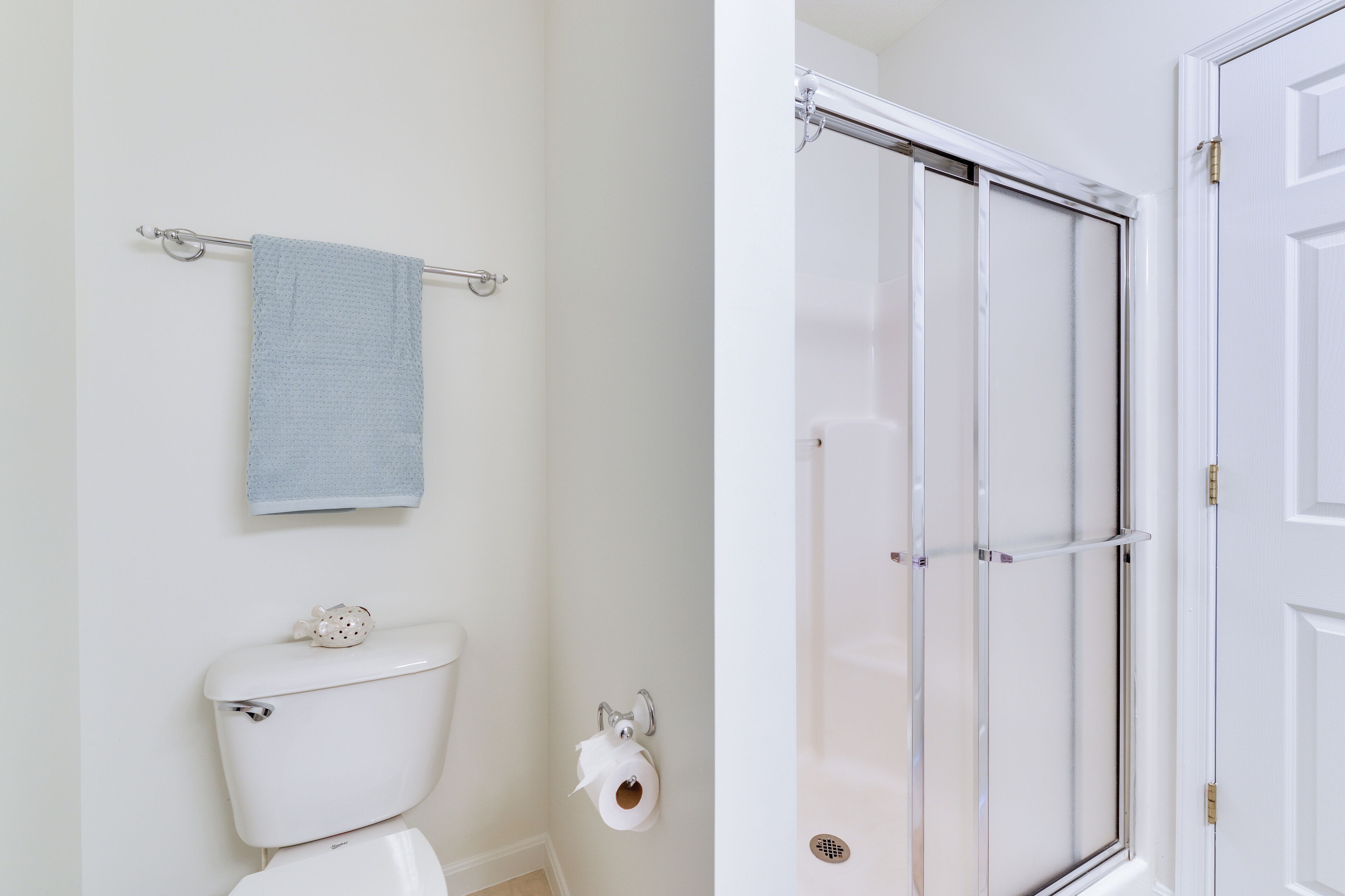 A bathroom with a toilet, a towel rack with a towel, and a shower area with a glass door.
