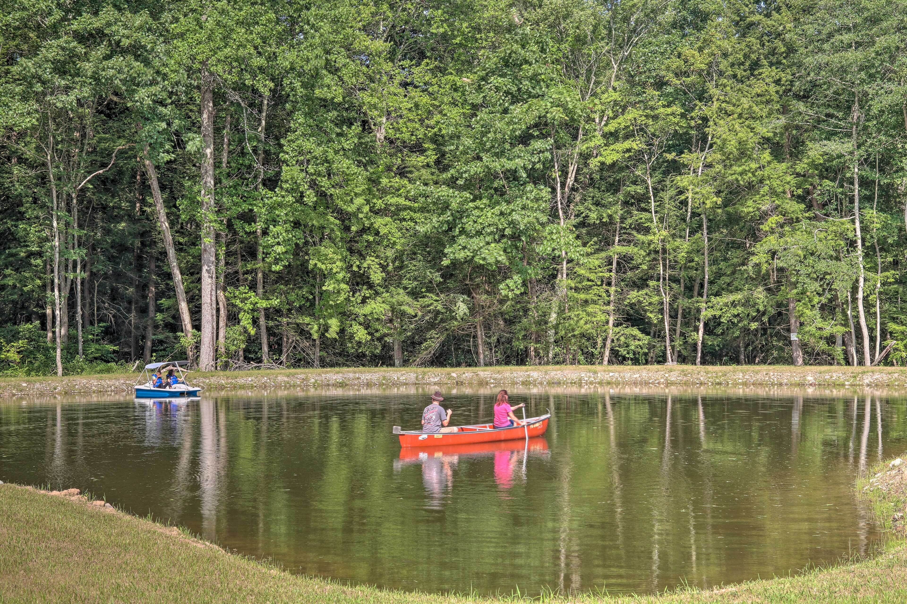 Ein ruhiger See mit zwei Booten, umgeben von dichtem Wald.