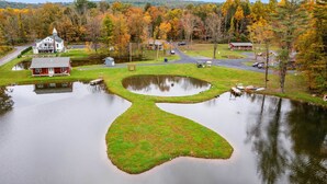 A lakeside property with a pond, a red house, and a white house with a tower.