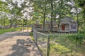 A residential area with two houses, a paved driveway, and a fenced yard.
