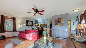 A spacious living room with a red sofa, a glass-top coffee table, and a ceiling fan. - 1 Mile to Golfing: Porch w/ Fireplace + Mtn Views! (Maggie Valley)