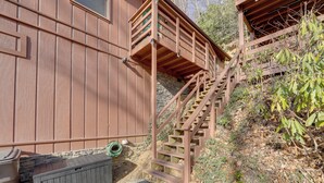 A wooden staircase leading to a balcony, a stone wall, and a wooden bench.
