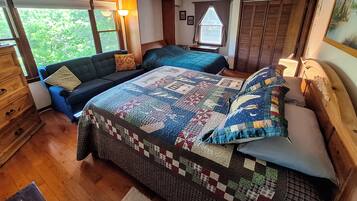 A bedroom with a large bed, a sofa, a dresser, and a window with curtains.