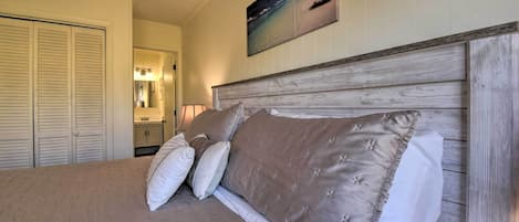 A bedroom with a bed, a wooden headboard, and a painting of a beach scene.