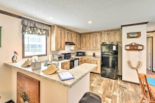 A kitchen with wooden cabinets, a refrigerator, a microwave, and a stove.