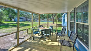 A covered patio with a table and chairs, overlooking a backyard with a lawn and a house. - 'pelican Place' Coastal Cottage Walk to Back Sound (Harkers Island)
