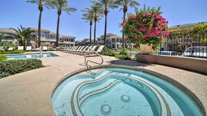 Une piscine avec des chaises longues, des palmiers et un jardinier.