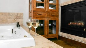 A bathroom with a bathtub, wooden cabinet, and a fireplace. - Stonebridge 2: 2 Blocks to Main, Shared Hot Tub (Fredericksburg)
