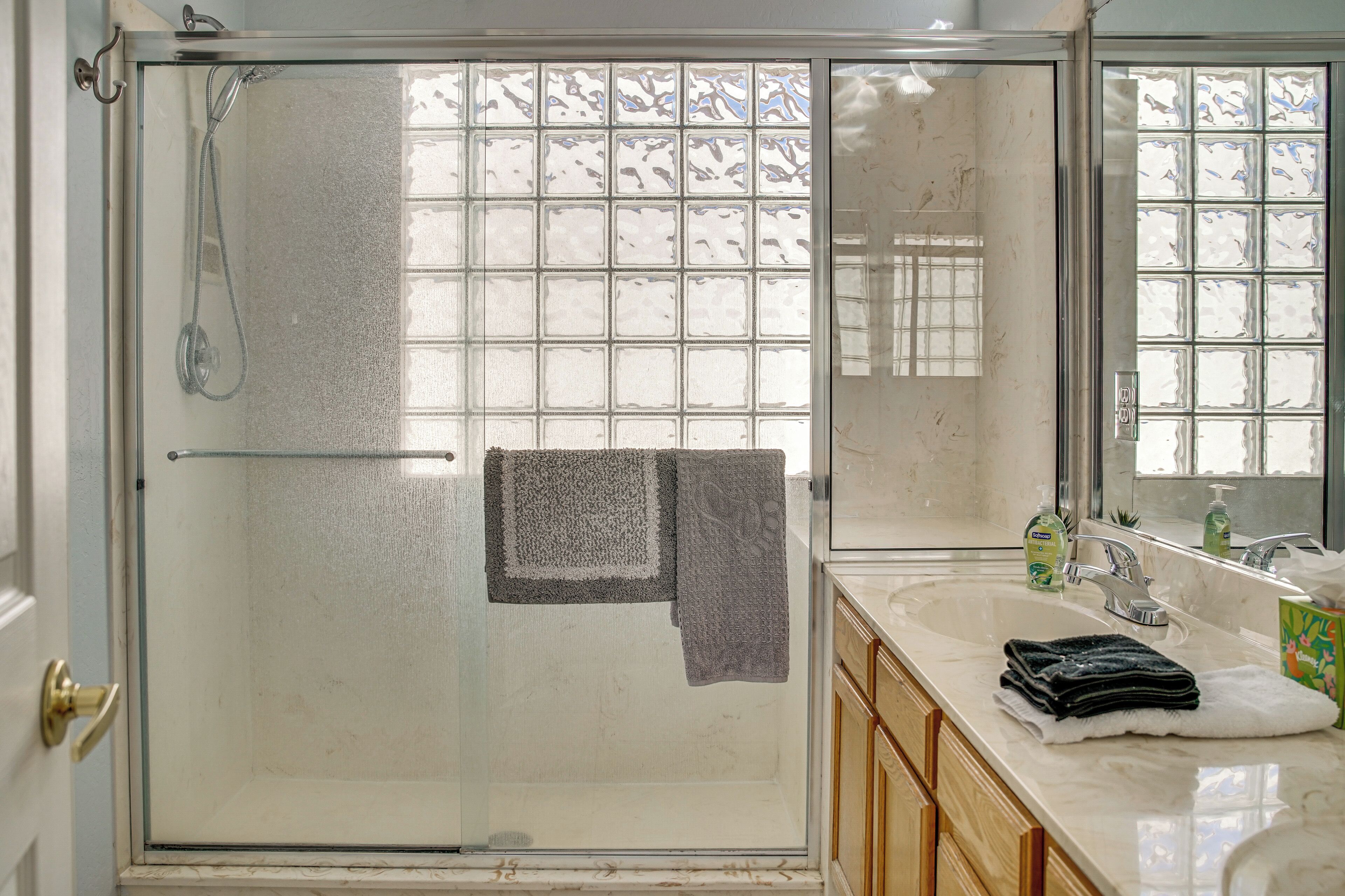 Een badkamer met een douchecabine van glas, een grote spiegel en een wastafel met een handdoekhouder.