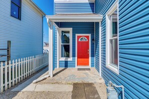 A blue house with a red door, white picket fence, and a small porch.
