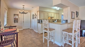 A spacious kitchen with white cabinets, a central island, and a dining area with wooden chairs. - Home in Historic Waxahachie w/ Yard & Patio! (Waxahachie)