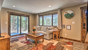 A cozy living room with a sofa, coffee table, and a large window with curtains. - Luxe Updated Home w/ Grill + Hot Tub: 4 Mi to Rmnp (Estes Park)