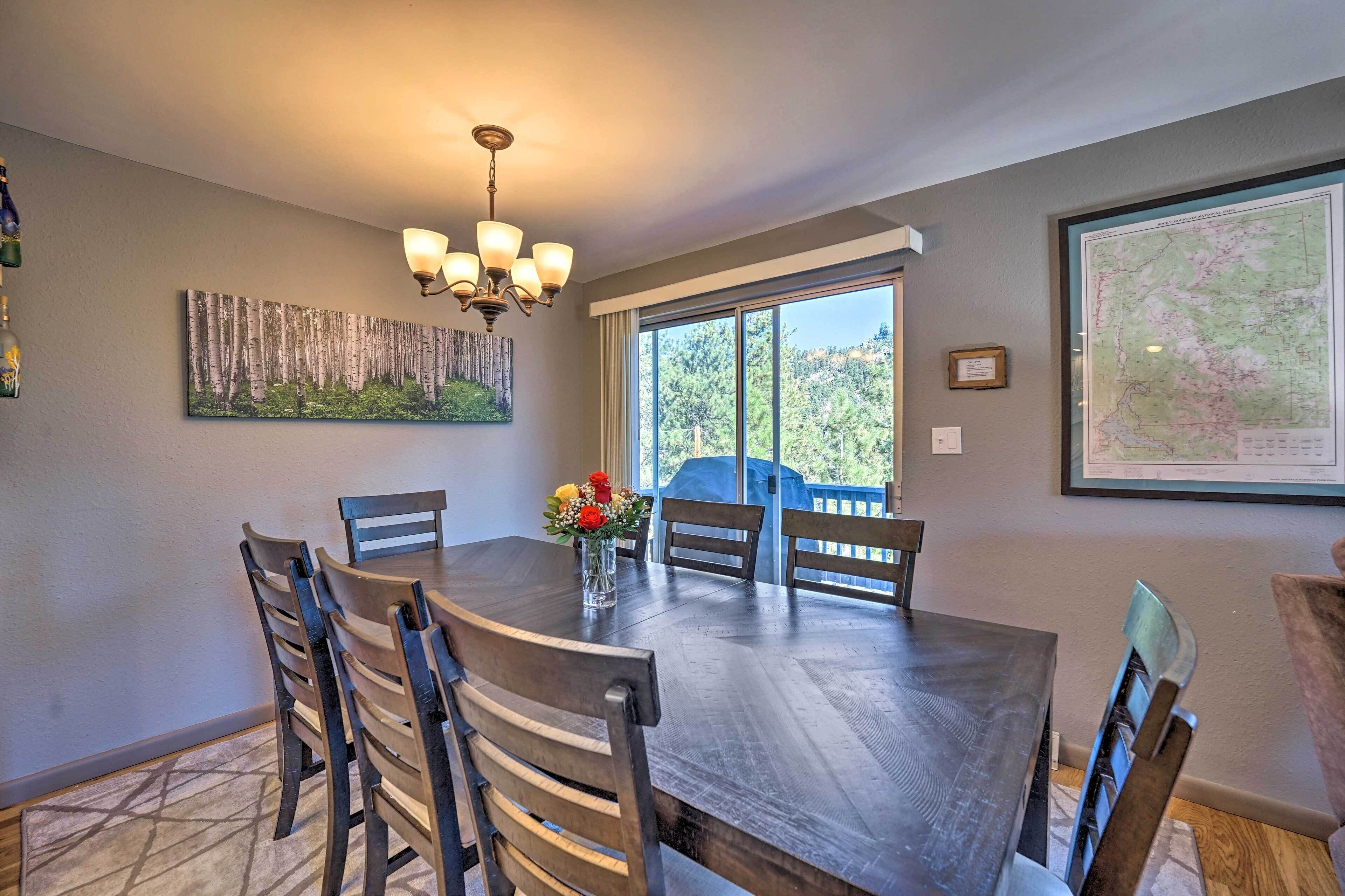 A dining area with a large table, chairs, a chandelier, a painting, and a map on the wall.