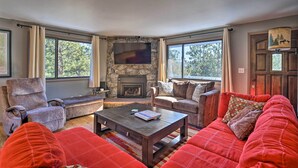 A cozy living room with a stone fireplace, comfortable seating, and large windows. - Luxe Updated Home w/ Grill + Hot Tub: 4 Mi to Rmnp (Estes Park)