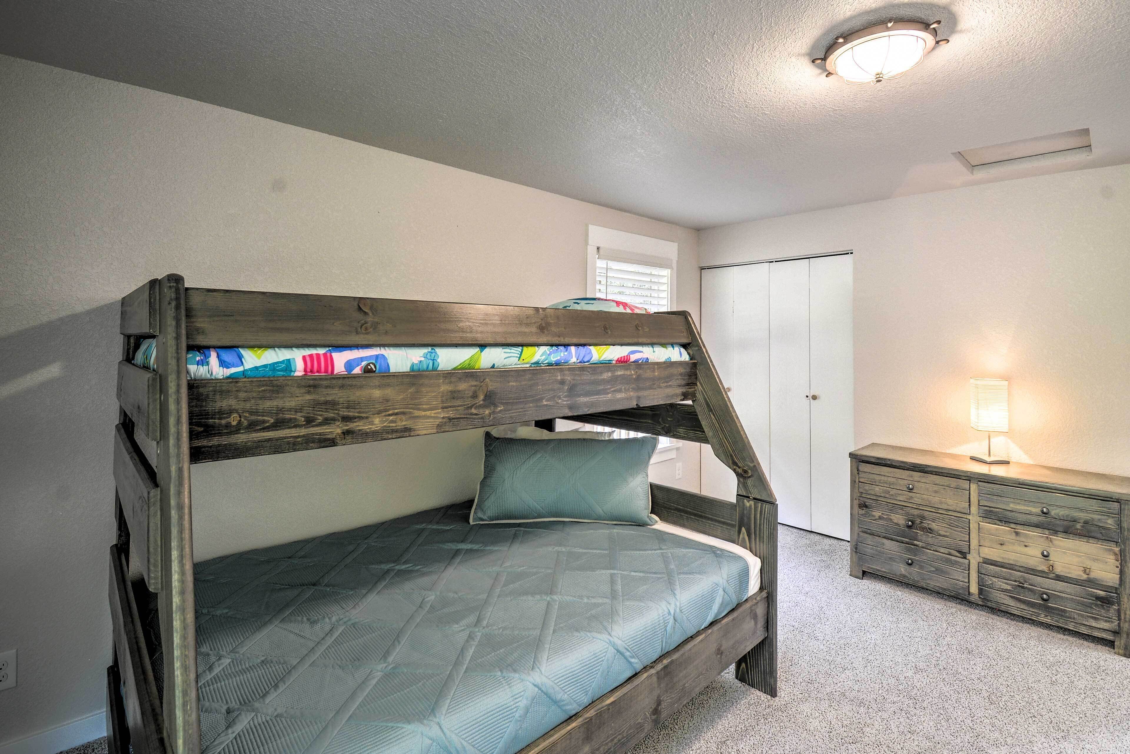 Un lit superposé avec un matelas matelassé et un oreiller, une commode avec des tiroirs, une lampe sur une table et une porte en arrière-plan.