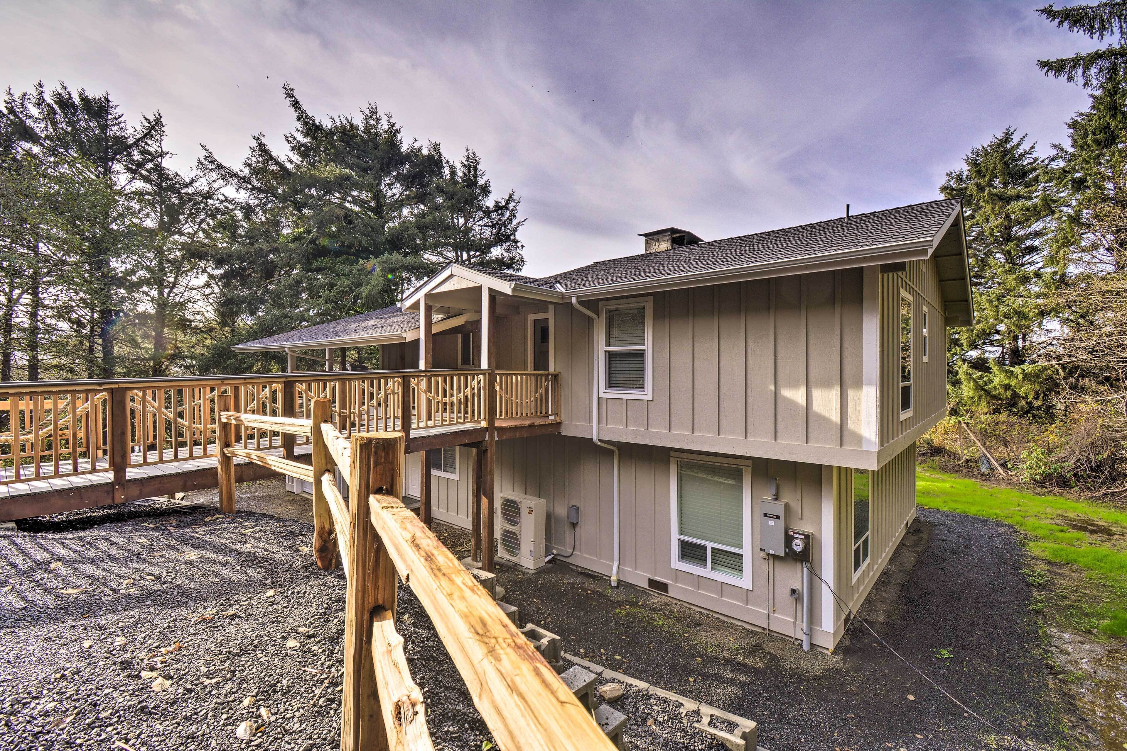 A two-story building with a balcony, outdoor air conditioning units, and a gravel driveway.