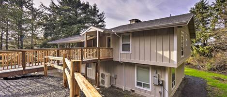 A two-story building with a balcony, outdoor air conditioning units, and a gravel driveway.