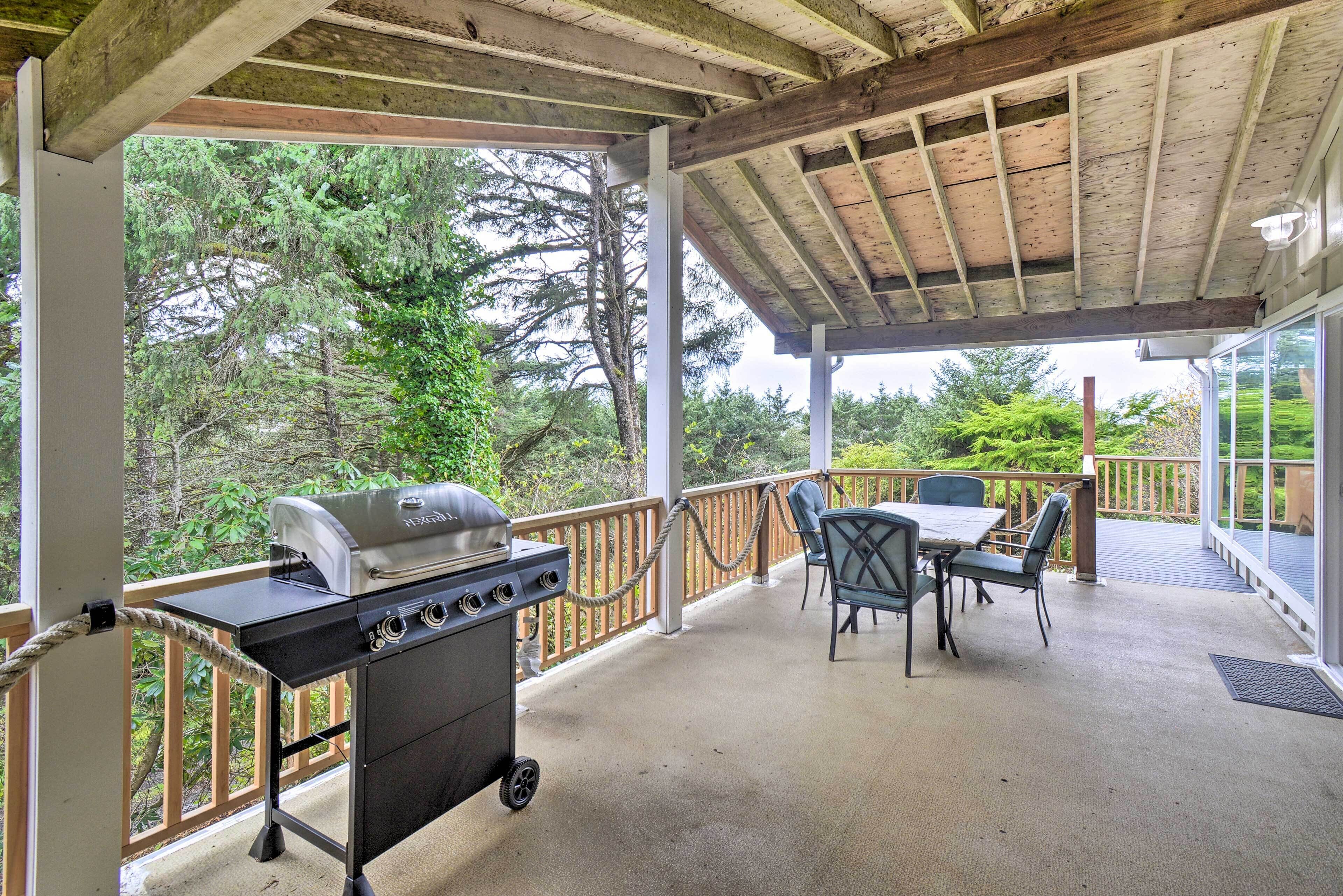 Patio esterno con barbecue, posti a sedere e vista sugli alberi.