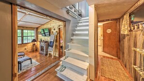 Una scala con gradini numerati che conduce a un secondo piano, un camino e interni in legno.