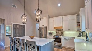 Una cocina moderna con armarios blancos, electrodomésticos de acero inoxidable y una isla de mármol.