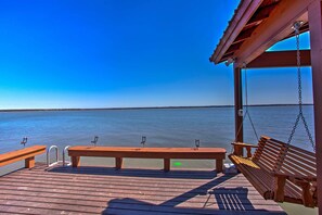 A wooden deck with a bench and a swing, overlooking a calm body of water. - Game Room + Lake Tawakoni Access: Family Getaway! (Quinlan)